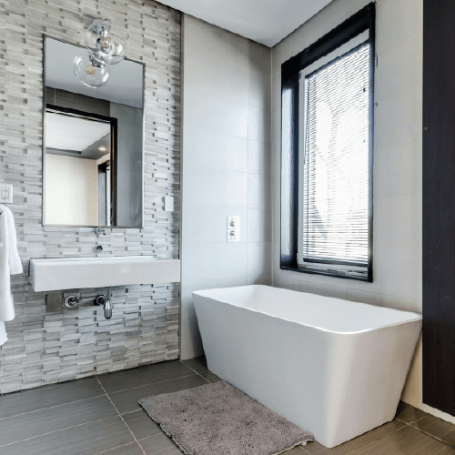 white ceramic bathtub near white framed window